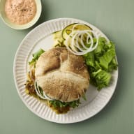 En tallrik innehåller en ett pitabröd med zucchinifritters, salladsblad, skivad lök och skivad zucchini.
