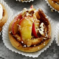 En tallrik med olika små bakverk och cupcakes står på ett bord tillsammans med skålar fyllda med godis och frukt.