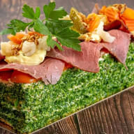 rostbiffstubbe uppdukad på ett mörkt träbord med rostbiff dekorerad med dill och grönsaker