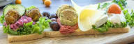 vegetarisk landgång på ljust bröd med grönsaksbullar ost och grönsaker uppdukat på ett ljust träbord