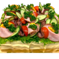 En smörgåstårta med salladsblad, kallskuret, ägg och grönsaker.