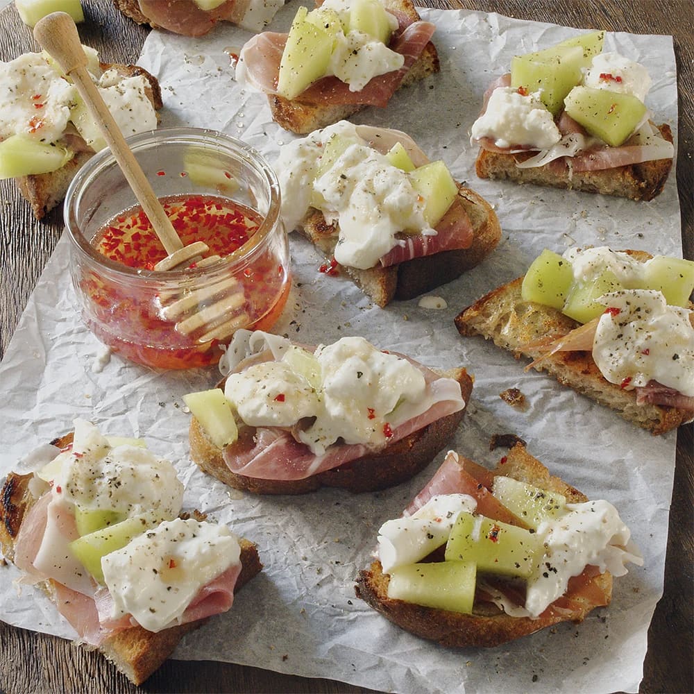 Toast med melon, burrata, chilihonung och prosciutto